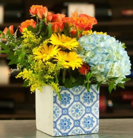 Paisley Pick me Up Bouquet is a cheerful bouquet perfect for any occasion calling for a smile. Blue hydrangea, orange Ecuadorian spray roses, yellow gerbera daisies, solidago asters, and mixed greenery. Delivered in an one sided cement paisley keepsake that is sure to please.