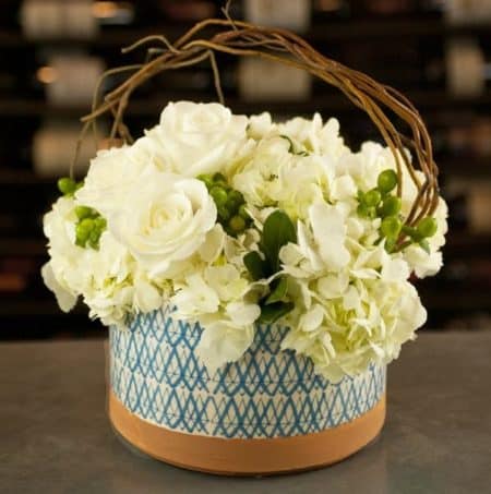 Our White Heron Aztec Design is designed in a unique keepsake ceramic bowl with white hydrangea, white Playa Blanca Ecuadorian roses, green hypericum berry, and mixture of greenery.