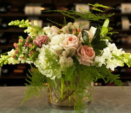 peach roses with greenery and white stock in a vase