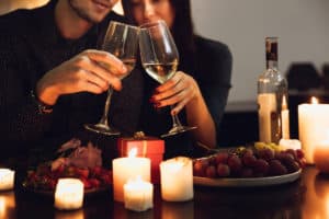 Couple on a romantic date with wine, candles, and grapes