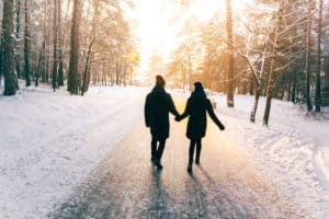 Two people walking in the snow holding hands