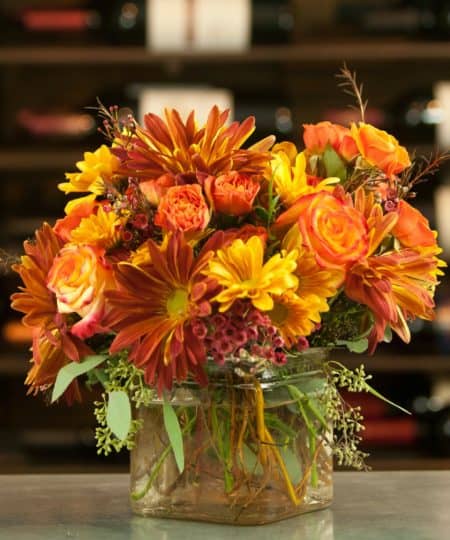 Vivid tones of red and copper mixed with peaches bring to mind the comfort following a mug of warm apple cider.  Includes a mix of fall colored daisies, carnations, and roses.  