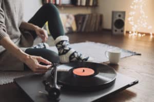 Woman listening music, relaxing, enjoying life at home. Girl wearing warm winter clothes having fun. Turntable playing vinyl LP record. Leisure, Christmas time, lockdown, retro revival, lifestyle
